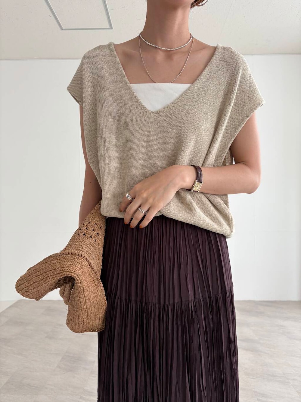 ホワイト系のキャミソール、ブラウン系のスカート、ベージュ系のベストを着用したレディースの夏コーディネートの6枚目の写真