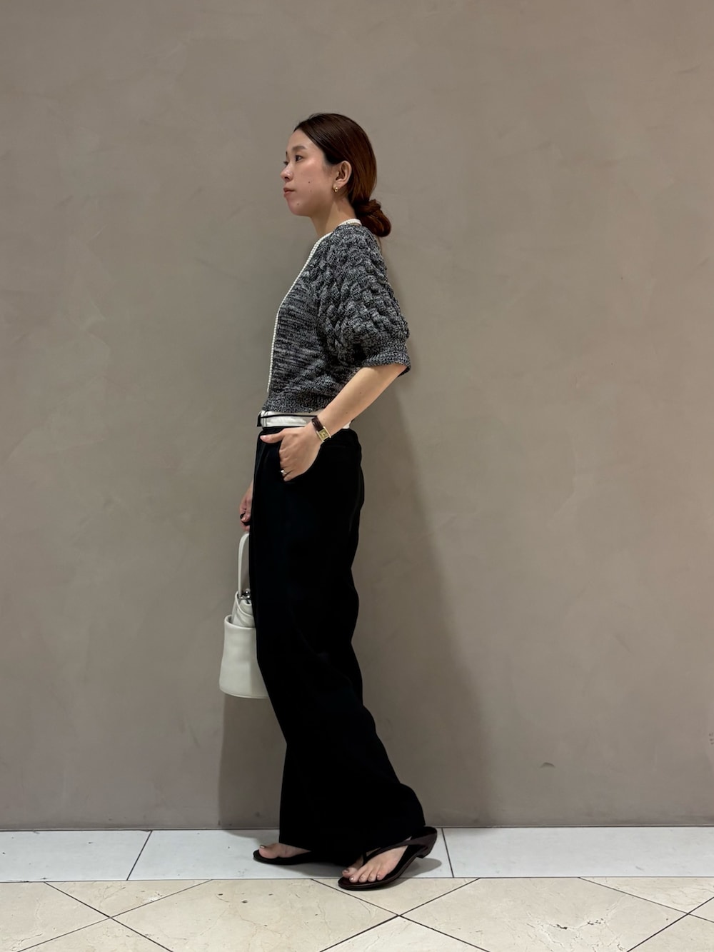 グレー系のニット/セーター、ブラック系のその他パンツ、ホワイト系のハンドバッグを着用したレディースの夏コーディネートの2枚目の写真