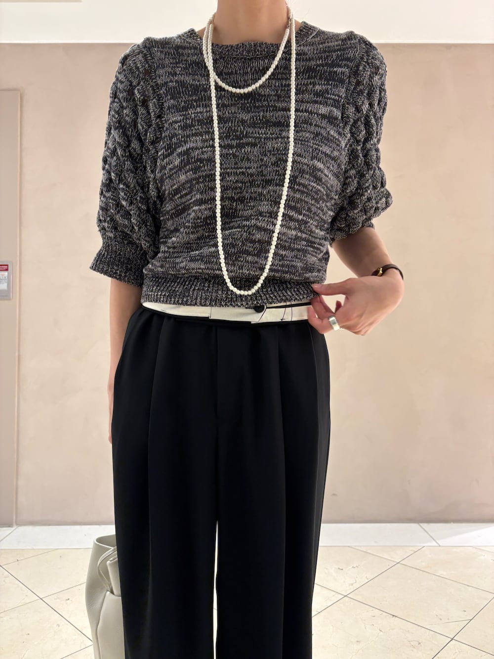 グレー系のニット/セーター、ブラック系のその他パンツ、ホワイト系のハンドバッグを着用したレディースの夏コーディネートの6枚目の写真