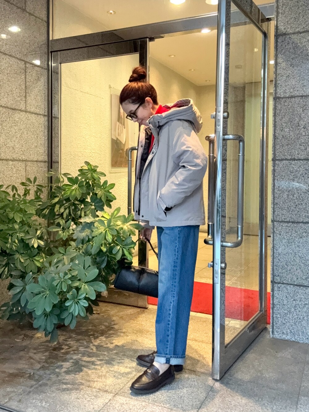 グレー系のダウンジャケット/コート、ブラック系のボストンバッグ、ブラウン系のローファーを着用したレディースの秋コーディネートの2枚目の写真