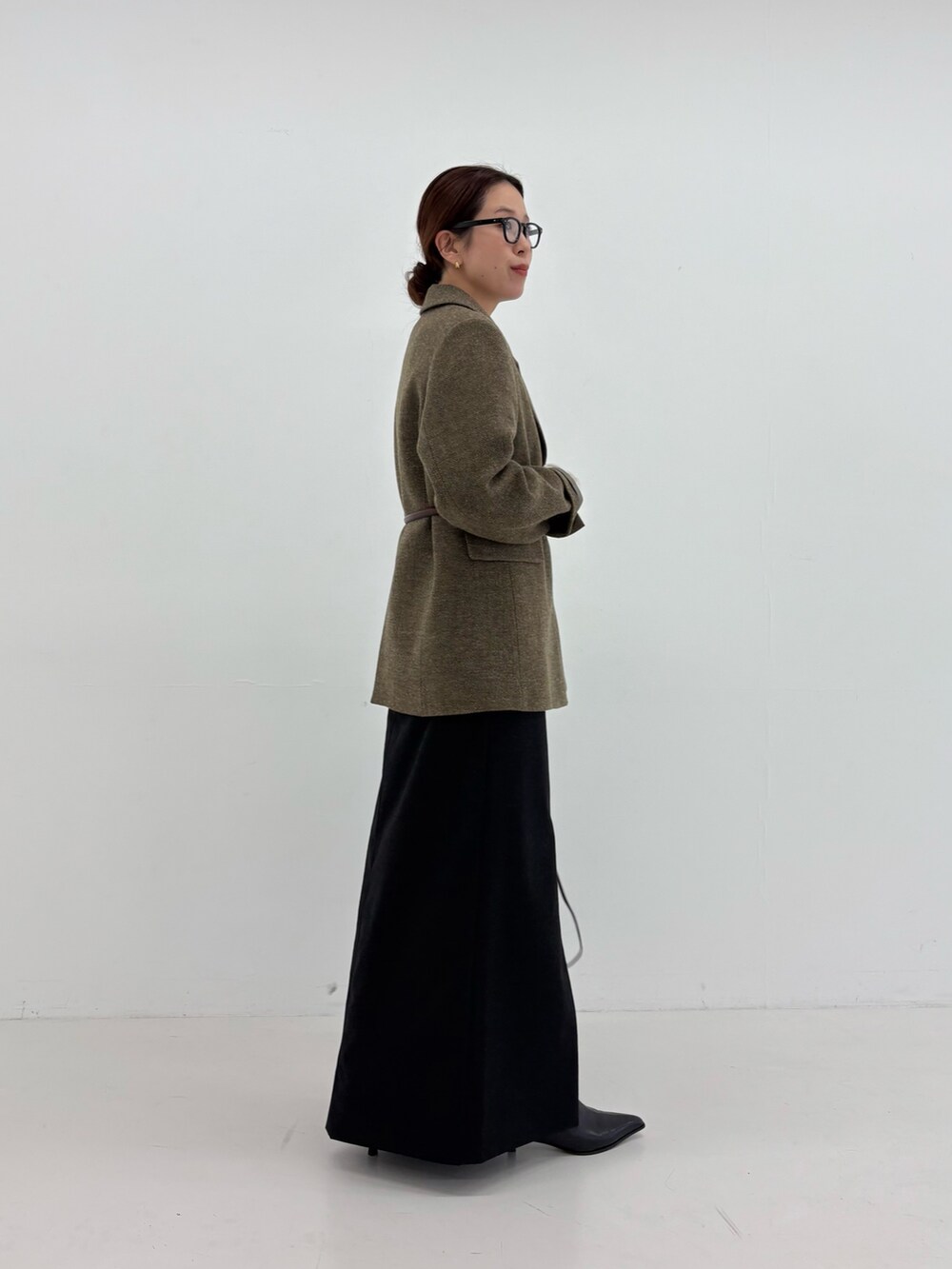 ブラック系のスカート、ブラック系のショルダーバッグ、グリーン系のその他アウターを着用したレディースの秋コーディネートの5枚目の写真