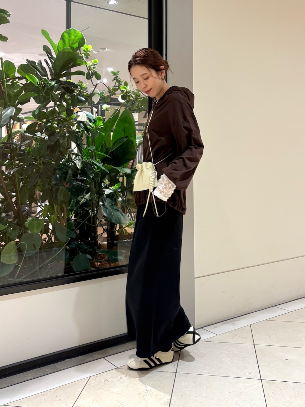 ブラウン系のパーカー、ホワイト系のスニーカー、ブラック系のスカートを着用したレディースの秋コーディネートの4枚目の写真