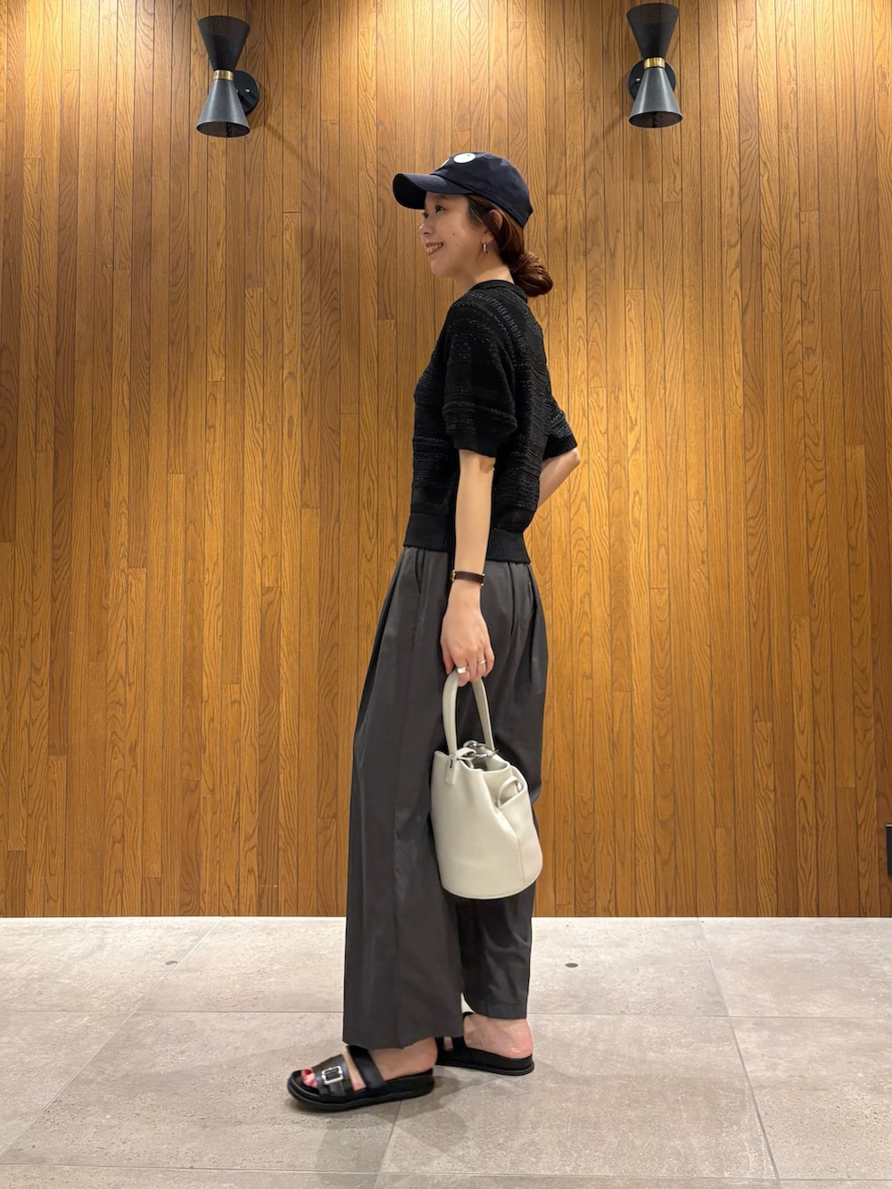 グレー系のその他パンツ、ブラック系のニット/セーター、ホワイト系のハンドバッグを着用したレディースの春コーディネートの2枚目の写真