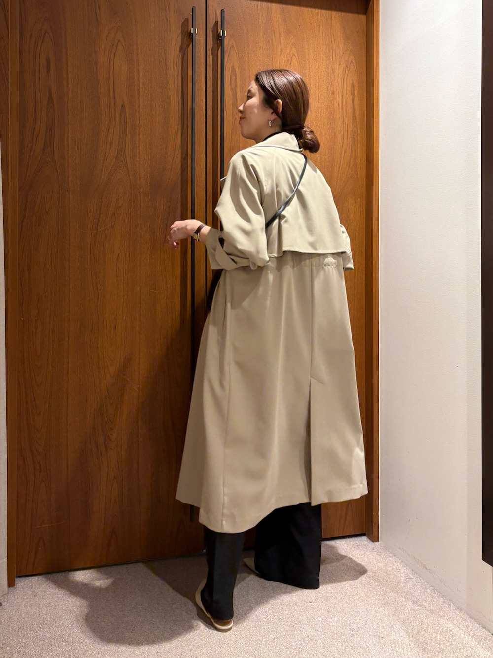 ベージュ系のトレンチコート、ブラック系のその他パンツ、ブラック系のその他アウターを着用したレディースの冬コーディネートの5枚目の写真