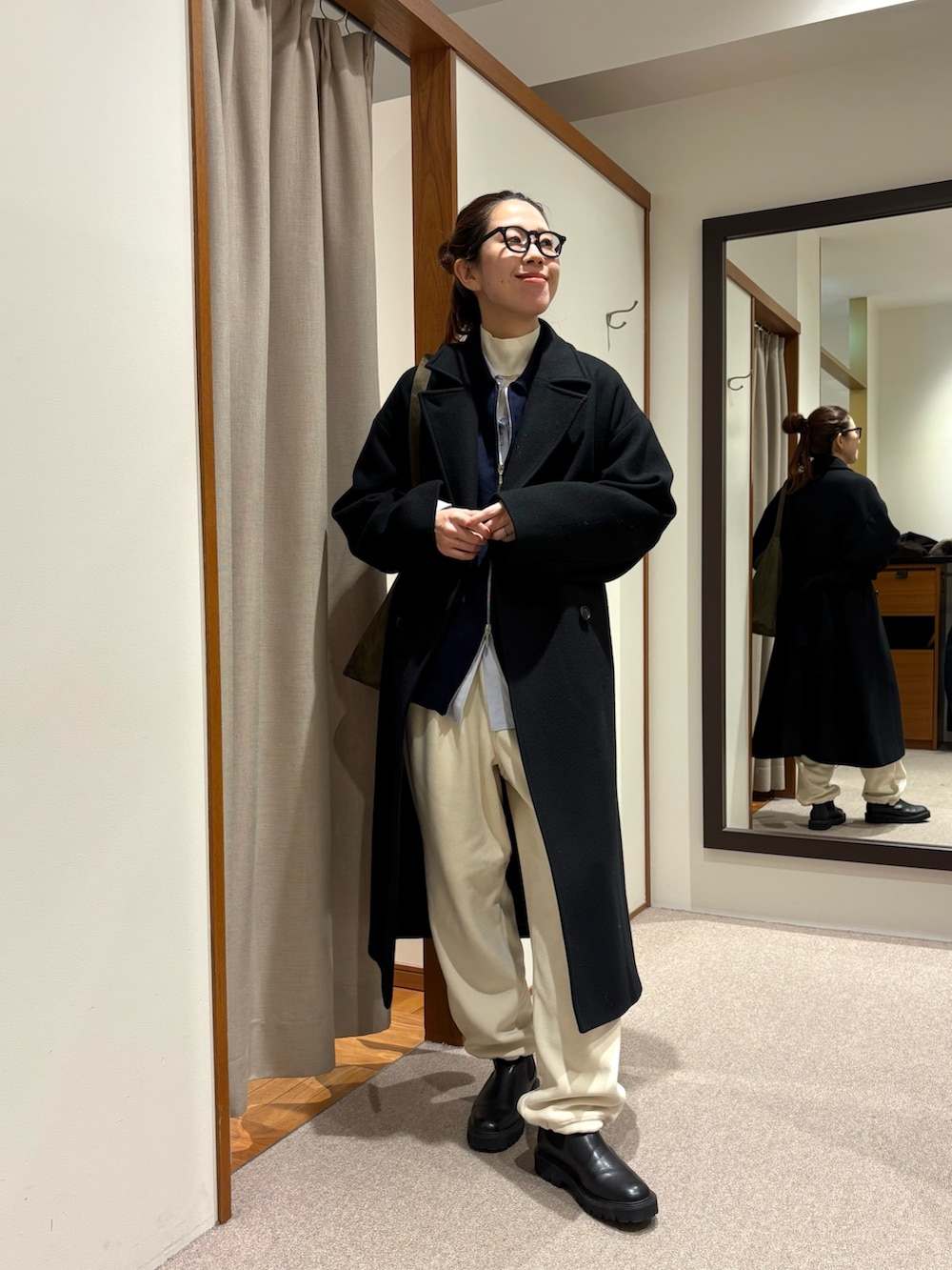 ブラック系のチェスターコート、ホワイト系のその他パンツ、ブラック系のブーツを着用したレディースの冬コーディネートの4枚目の写真