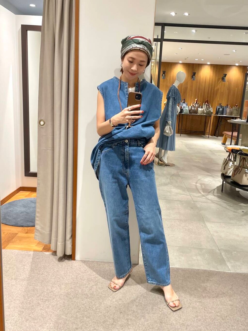 ホワイト系のタンクトップ、ブルー系のベスト、ブルー系のデニムパンツを着用したレディースの夏コーディネートの4枚目の写真