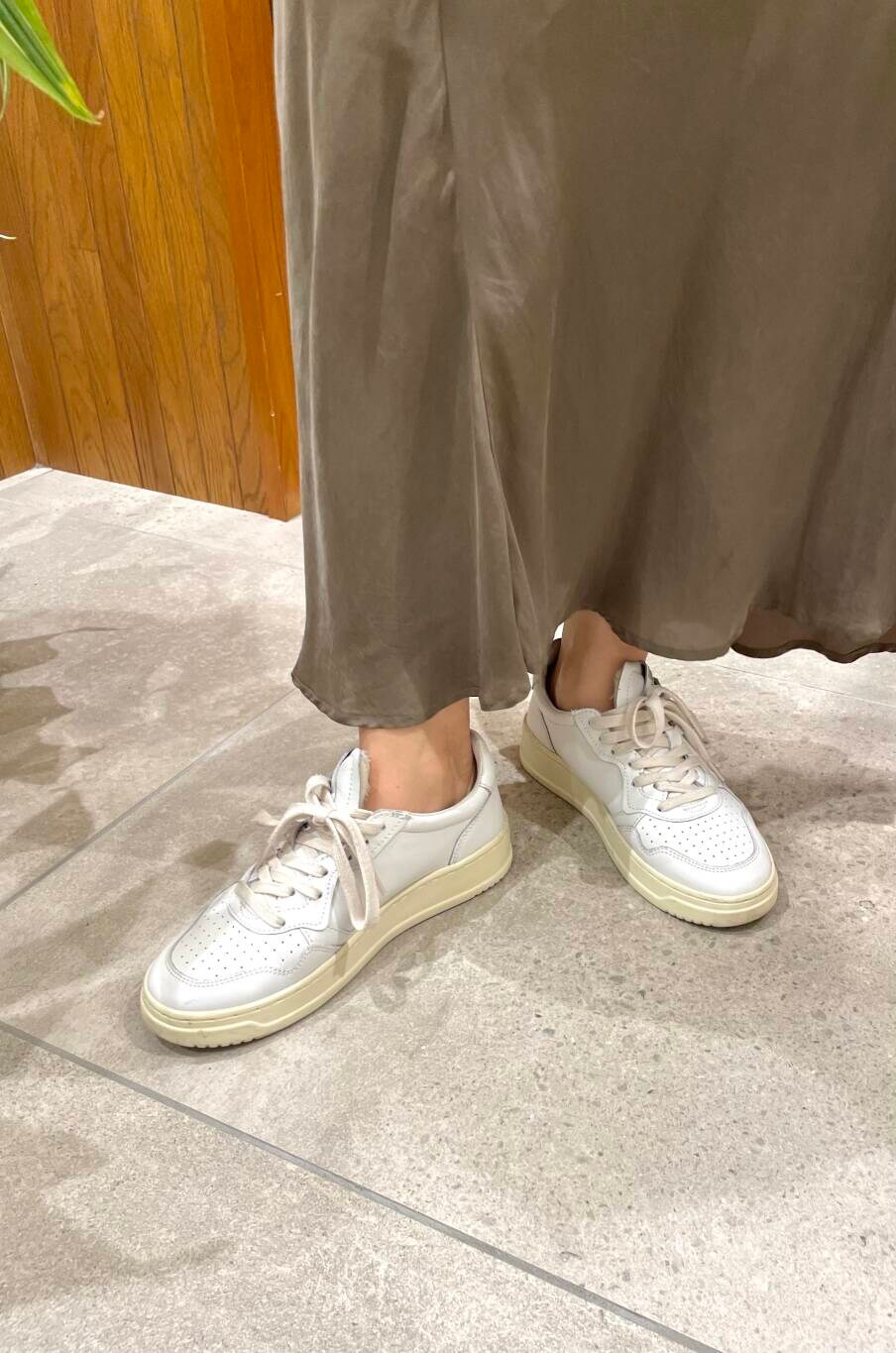 グリーン系のスカート、ブルー系のデニムジャケット、ホワイト系のスニーカーを着用したレディースの秋コーディネートの6枚目の写真