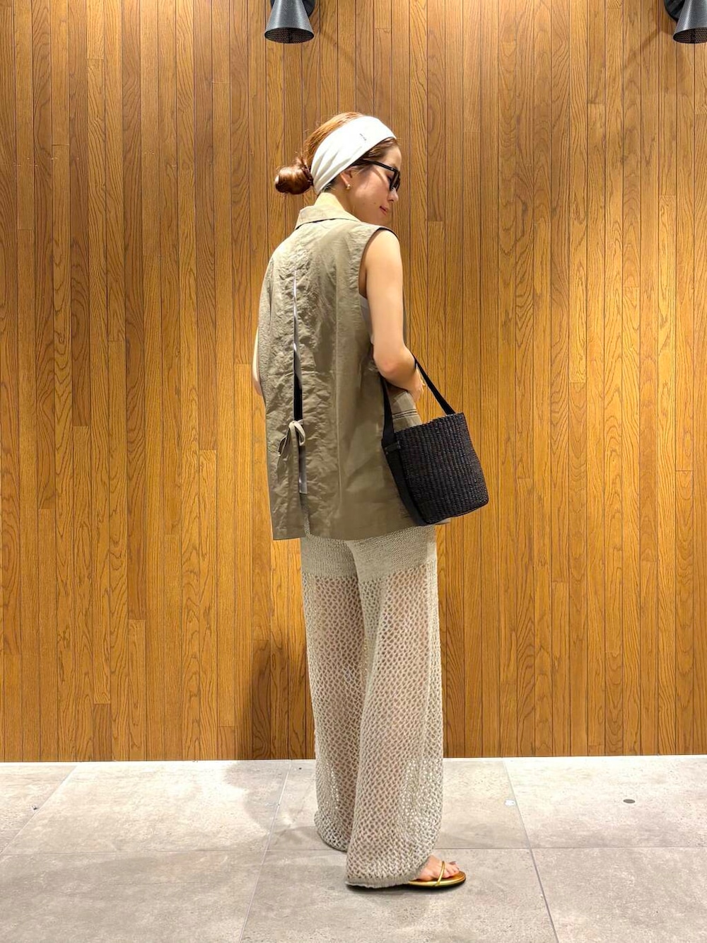 ブラック系のかごバッグ、ゴールド系のサンダル、グレー系のその他パンツを着用したレディースの夏コーディネートの3枚目の写真