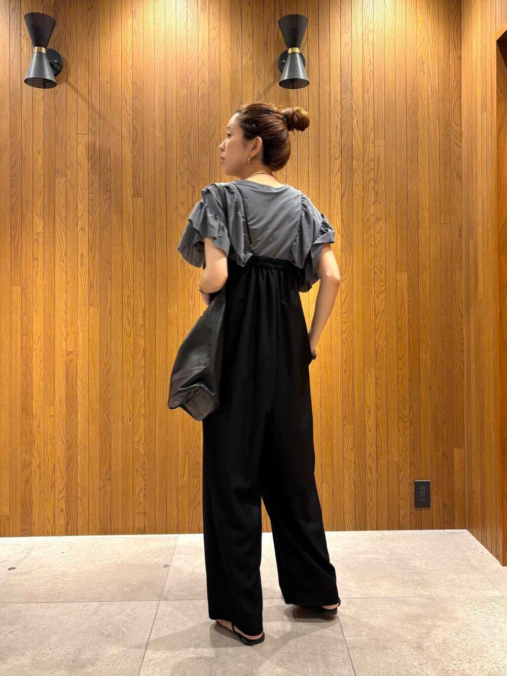 ブラック系のサロペット/オーバーオール、ブルー系のTシャツ/カットソー、ブラック系のサンダルを着用したレディースの夏コーディネートの3枚目の写真
