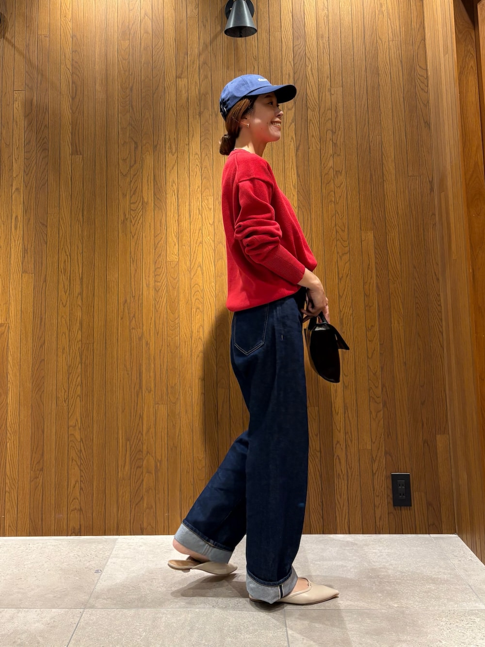 ブルー系のデニムパンツ、レッド系のニット/セーター、ブラック系のハンドバッグを着用したレディースの秋コーディネートの5枚目の写真