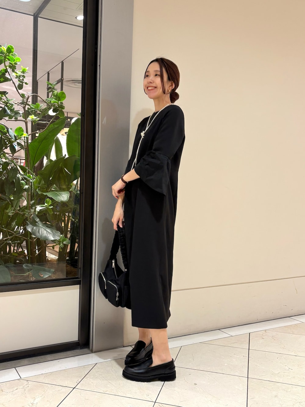 ブラック系のワンピース、ブラック系のローファー、ブラック系のショルダーバッグを着用したレディースの冬コーディネートの2枚目の写真