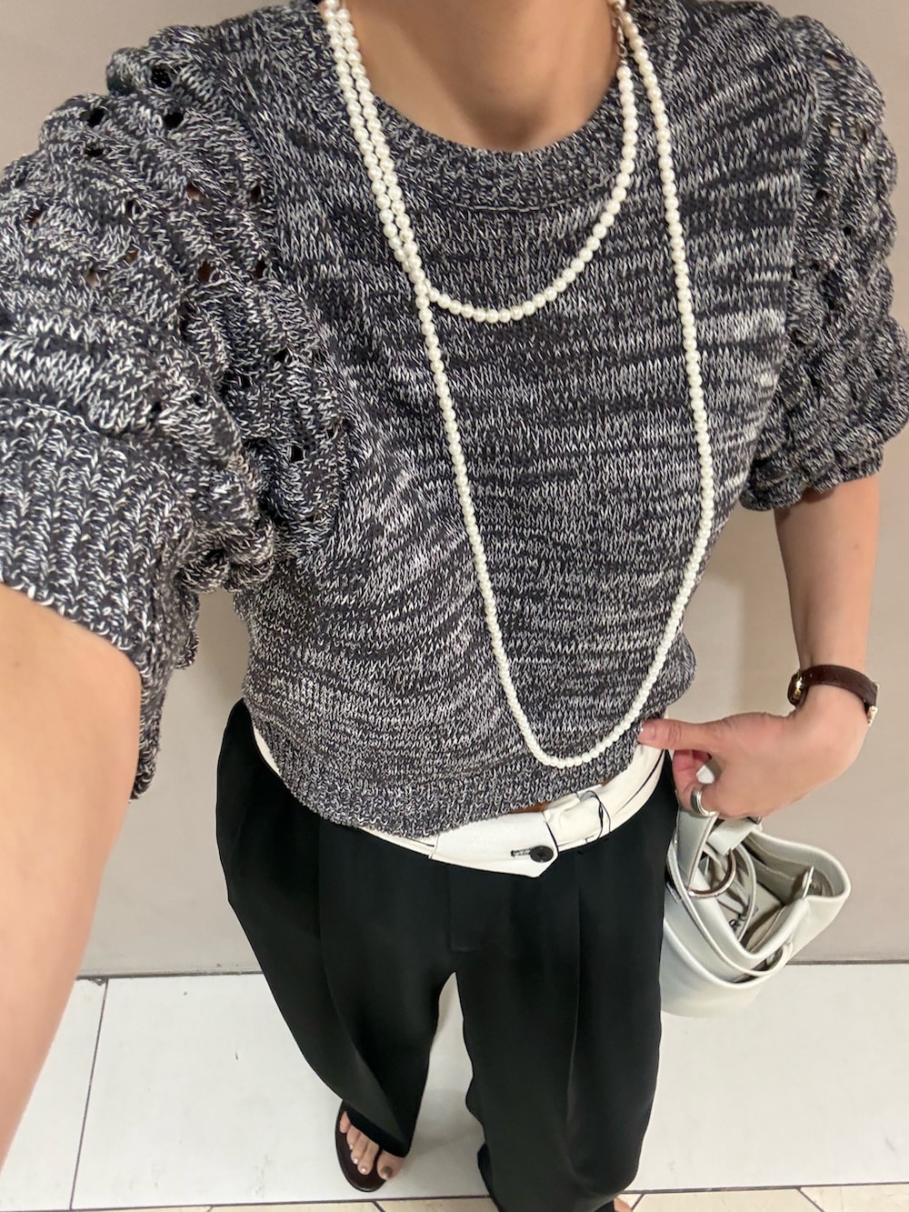 グレー系のニット/セーター、ブラック系のその他パンツ、ホワイト系のハンドバッグを着用したレディースの夏コーディネートの7枚目の写真