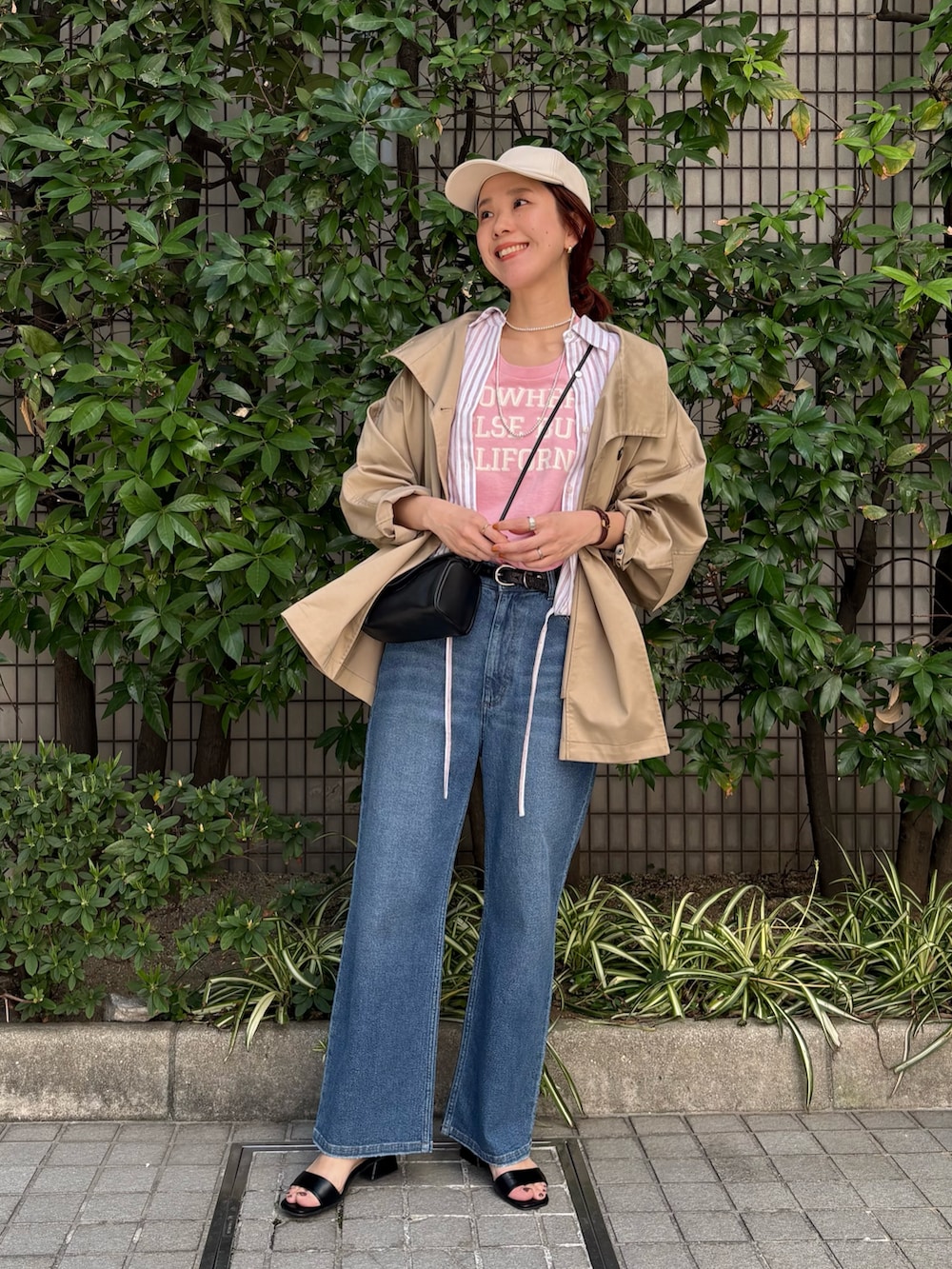 レッド系のシャツ/ブラウス、ベージュ系のトレンチコート、ブルー系のデニムパンツを着用したレディースの春コーディネートの4枚目の写真