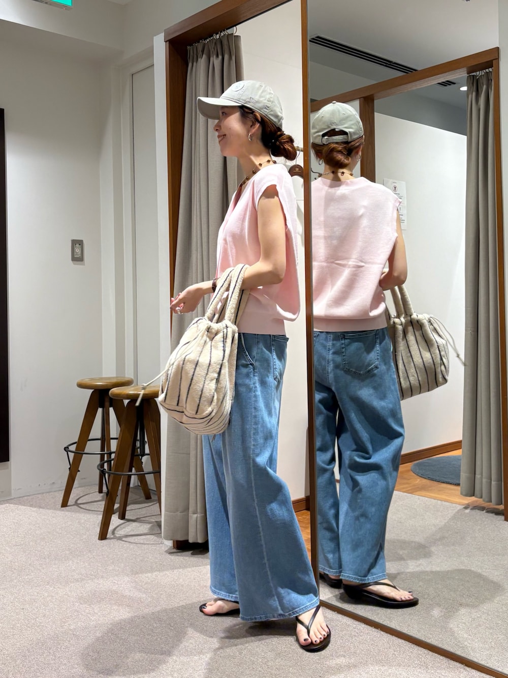 ブルー系のデニムパンツ、ピンク系のベスト、ホワイト系のハンドバッグを着用したレディースの夏コーディネートの2枚目の写真