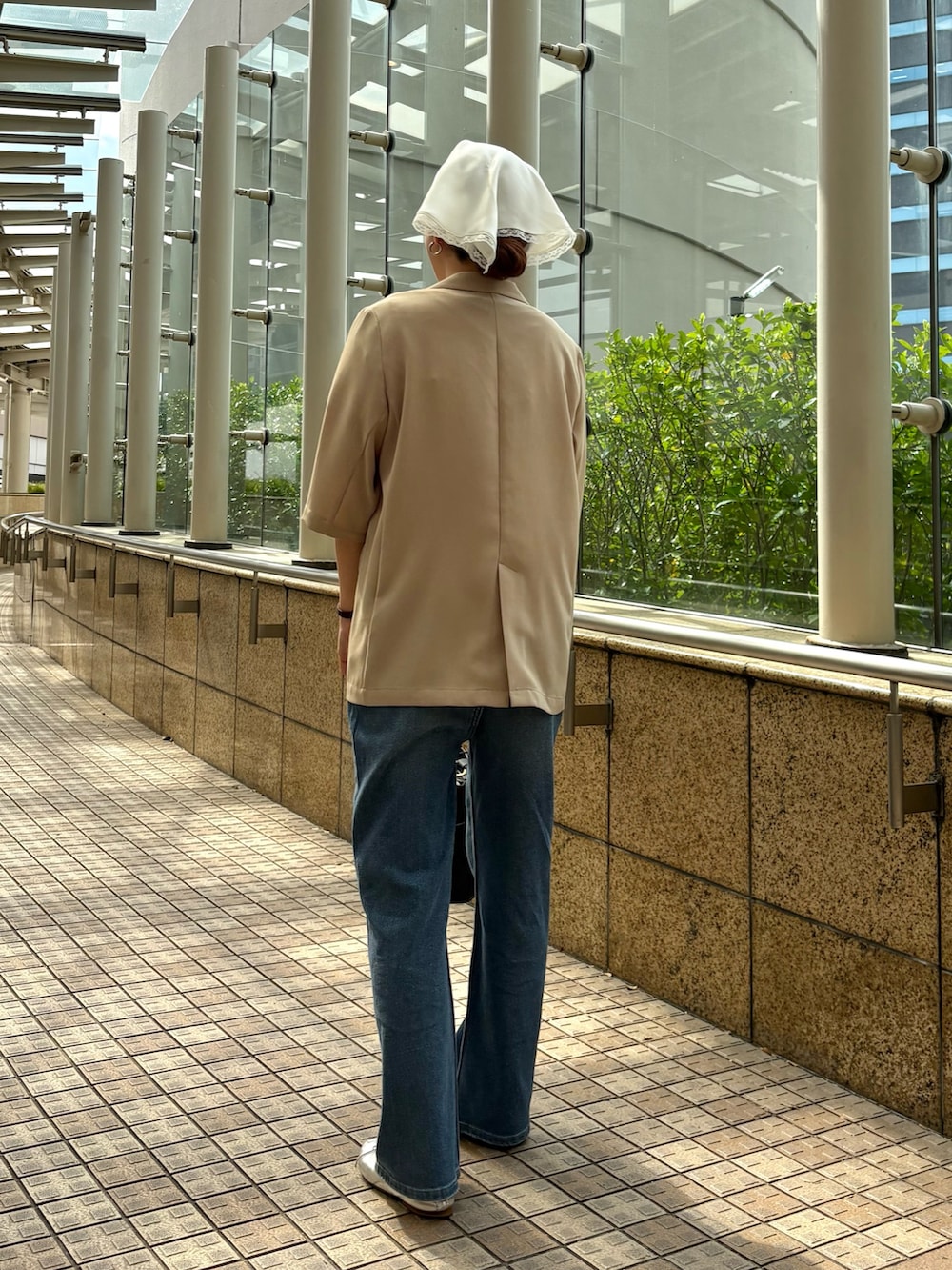 ブルー系のデニムパンツ、ベージュ系のその他アウター、ブラック系のハンドバッグを着用したレディースの春コーディネートの4枚目の写真
