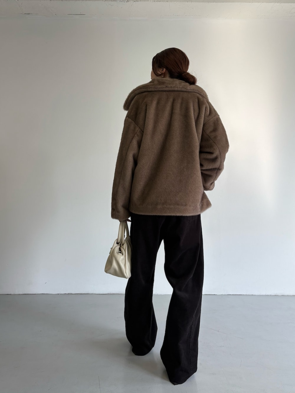 グレー系のその他パンツ、レッド系のニット/セーター、ブラック系のハンドバッグを着用したレディースの冬コーディネートの5枚目の写真