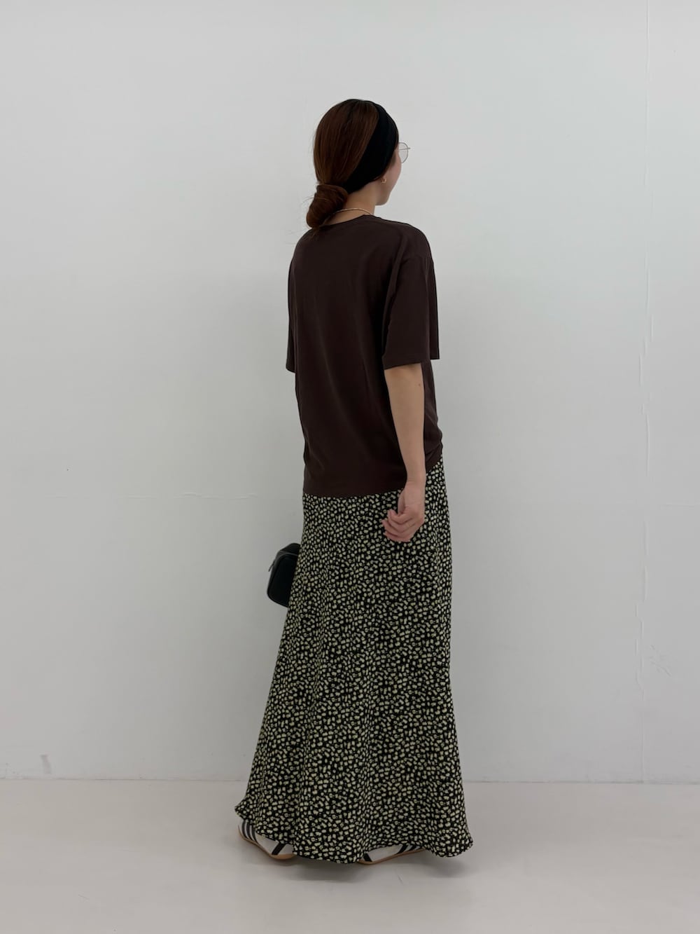 ブラウン系のTシャツ/カットソー、イエロー系のスカート、ブラック系のハンドバッグを着用したレディースの夏コーディネートの3枚目の写真