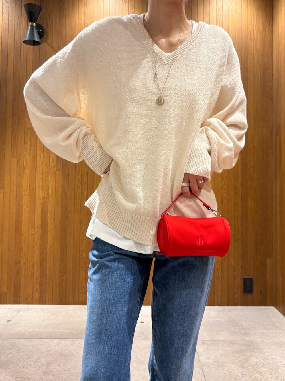 ベージュ系のニット/セーター、ホワイト系のTシャツ/カットソー、レッド系のハンドバッグを着用したレディースの秋コーディネートの6枚目の写真