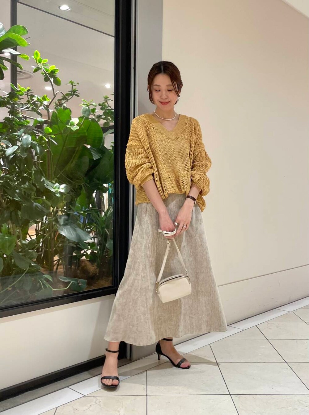 ホワイト系のショルダーバッグ、ベージュ系のスカート、イエロー系のニット/セーターを着用したレディースの冬コーディネートの3枚目の写真
