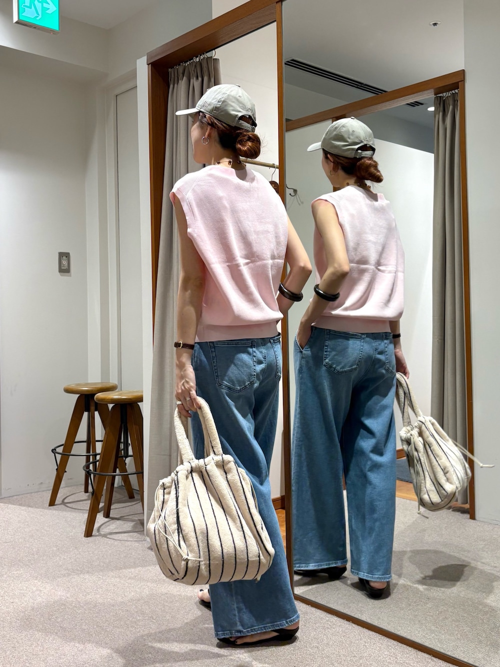 ブルー系のデニムパンツ、ピンク系のベスト、ホワイト系のハンドバッグを着用したレディースの夏コーディネートの3枚目の写真