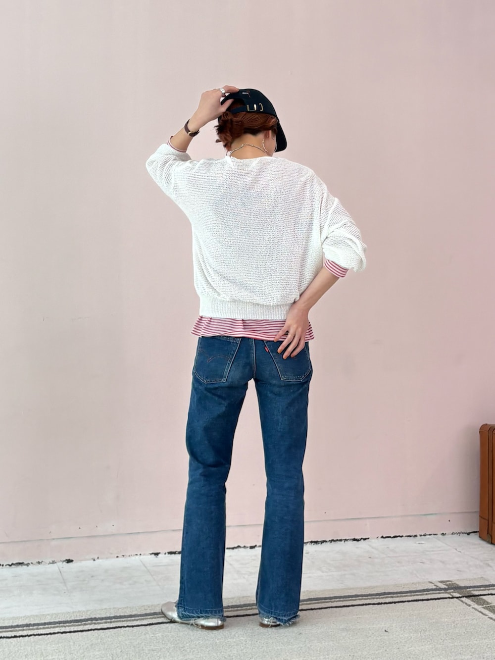 レッド系のTシャツ/カットソー、ホワイト系のニット/セーター、ブルー系のキャップを着用したレディースの春コーディネートの3枚目の写真