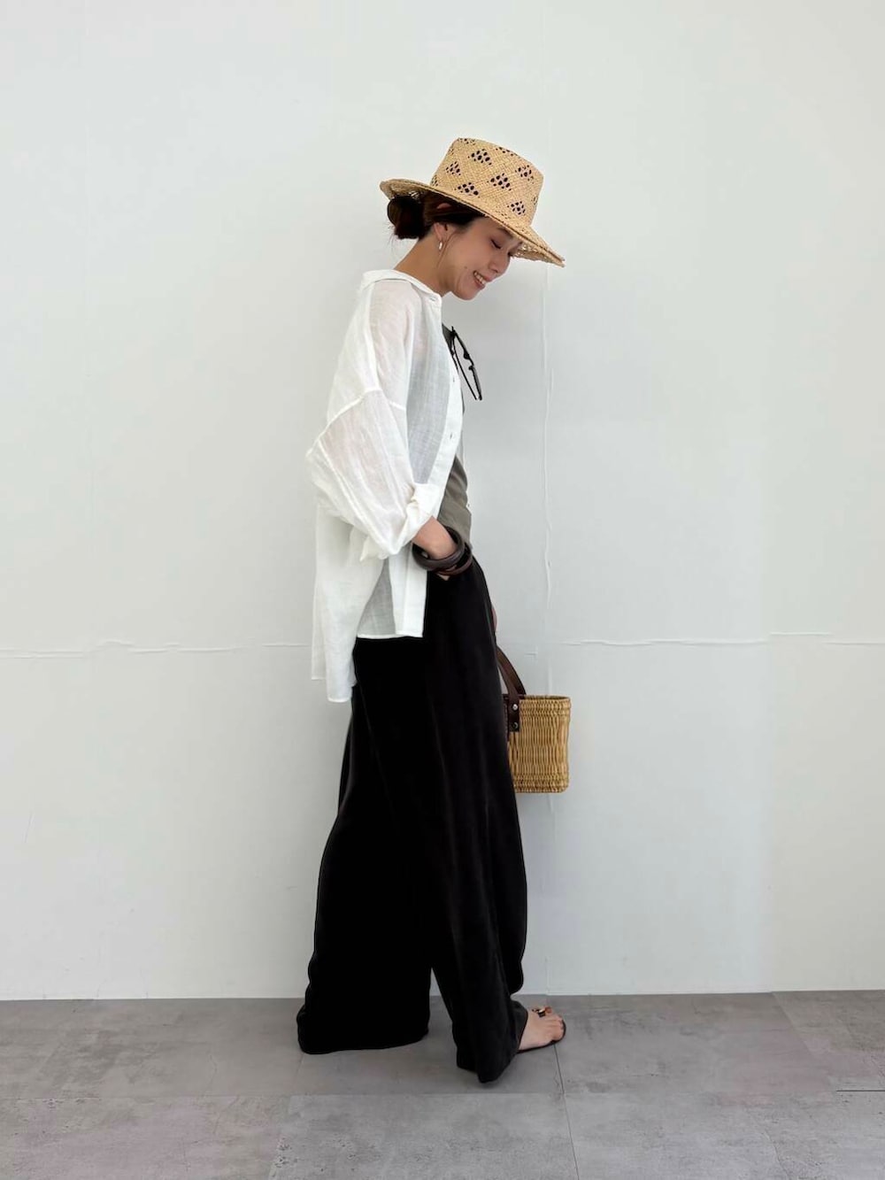 ブラウン系のかごバッグ、ホワイト系のシャツ/ブラウス、ブラック系のサンダルを着用したレディースの夏コーディネートの5枚目の写真