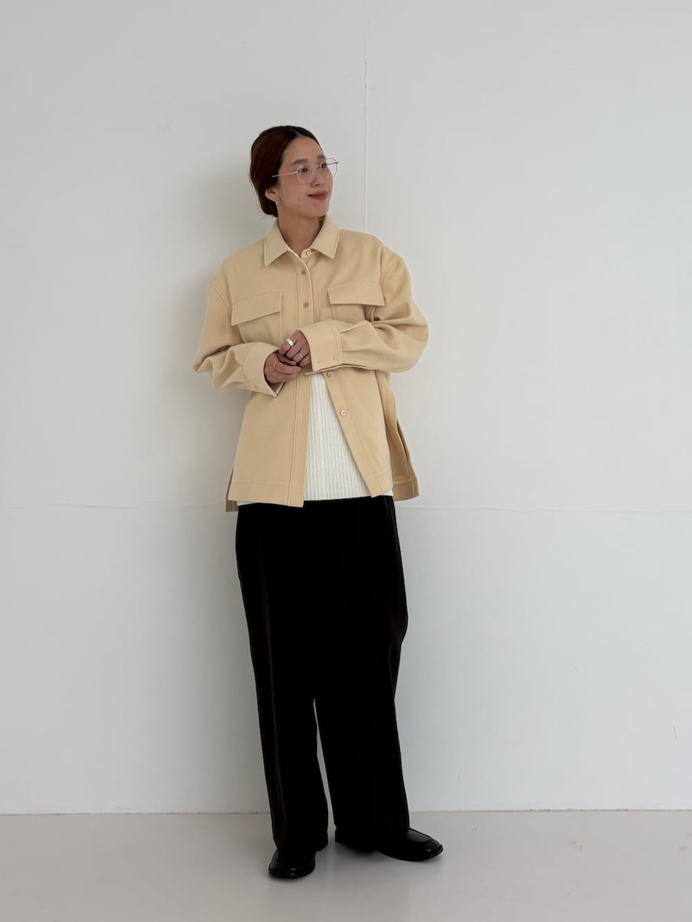 ホワイト系のニット/セーター、ブラウン系のその他パンツ、ゴールド系のメガネを着用したレディースの秋コーディネートの6枚目の写真