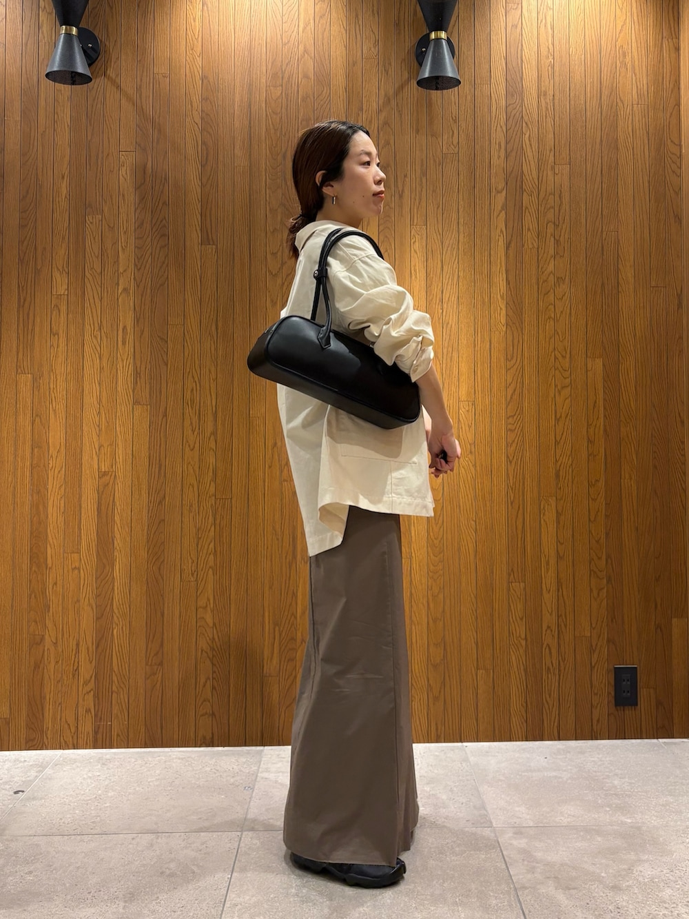 グレー系のスカート、その他のニット/セーター、ブラック系のスニーカーを着用したレディースの春コーディネートの2枚目の写真