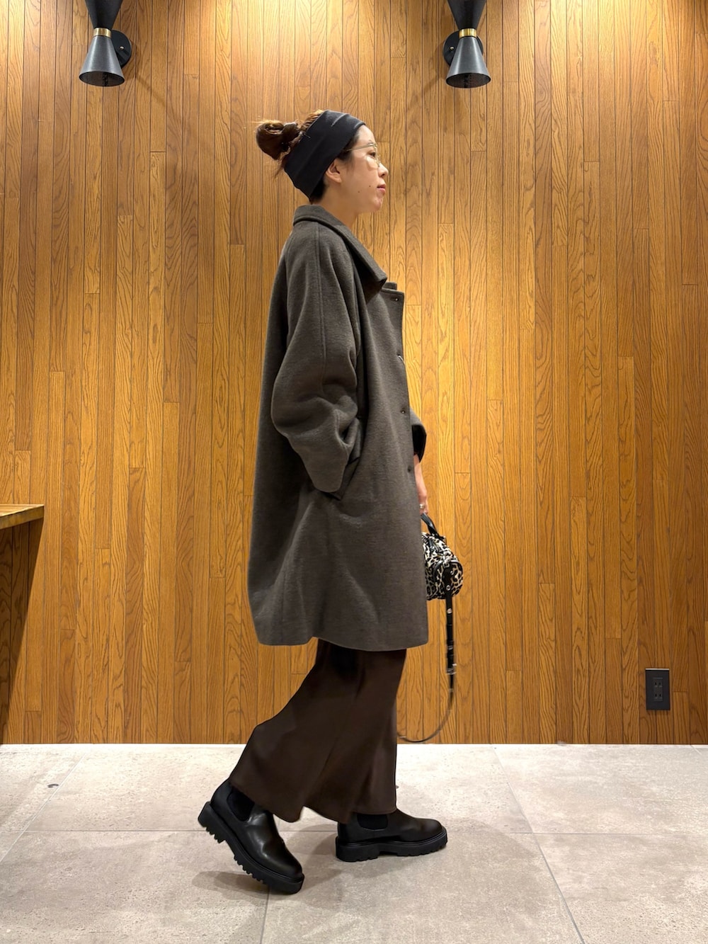 グリーン系のステンカラーコート、ブラウン系のスカート、その他のハンドバッグを着用したレディースの冬コーディネートの5枚目の写真