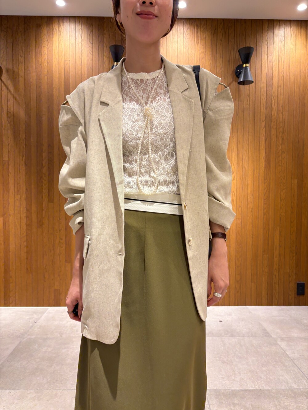 グリーン系のスカート、ブラック系のブーツ、ホワイト系のその他アウターを着用したレディースの秋コーディネートの5枚目の写真