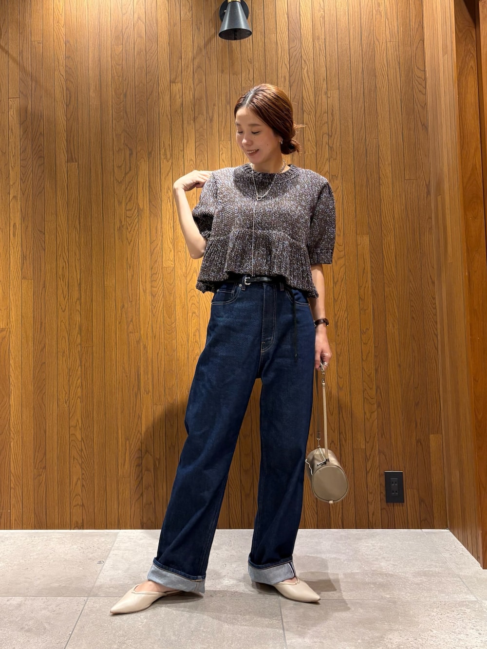 ブルー系のデニムパンツ、ブラウン系のニット/セーター、ベージュ系のハンドバッグを着用したレディースの秋コーディネートの7枚目の写真