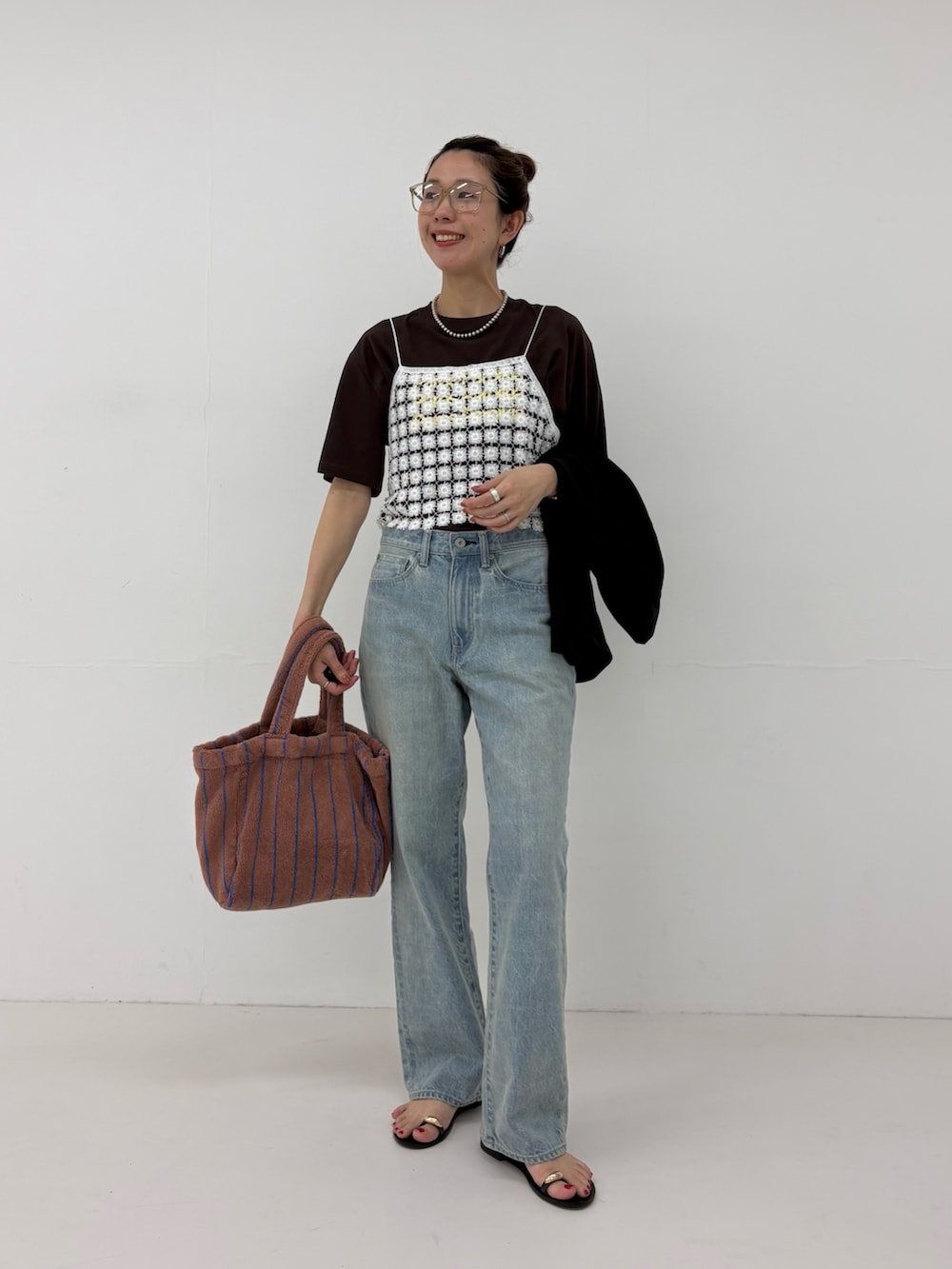 ブルー系のデニムパンツ、ホワイト系のその他トップス、イエロー系のハンドバッグを着用したレディースの春コーディネートの4枚目の写真