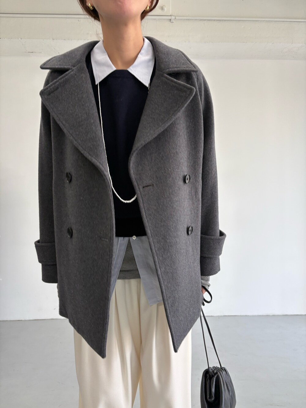 グレー系のピーコート、ホワイト系のその他パンツ、シルバー系のショルダーバッグを着用したレディースの冬コーディネートの7枚目の写真