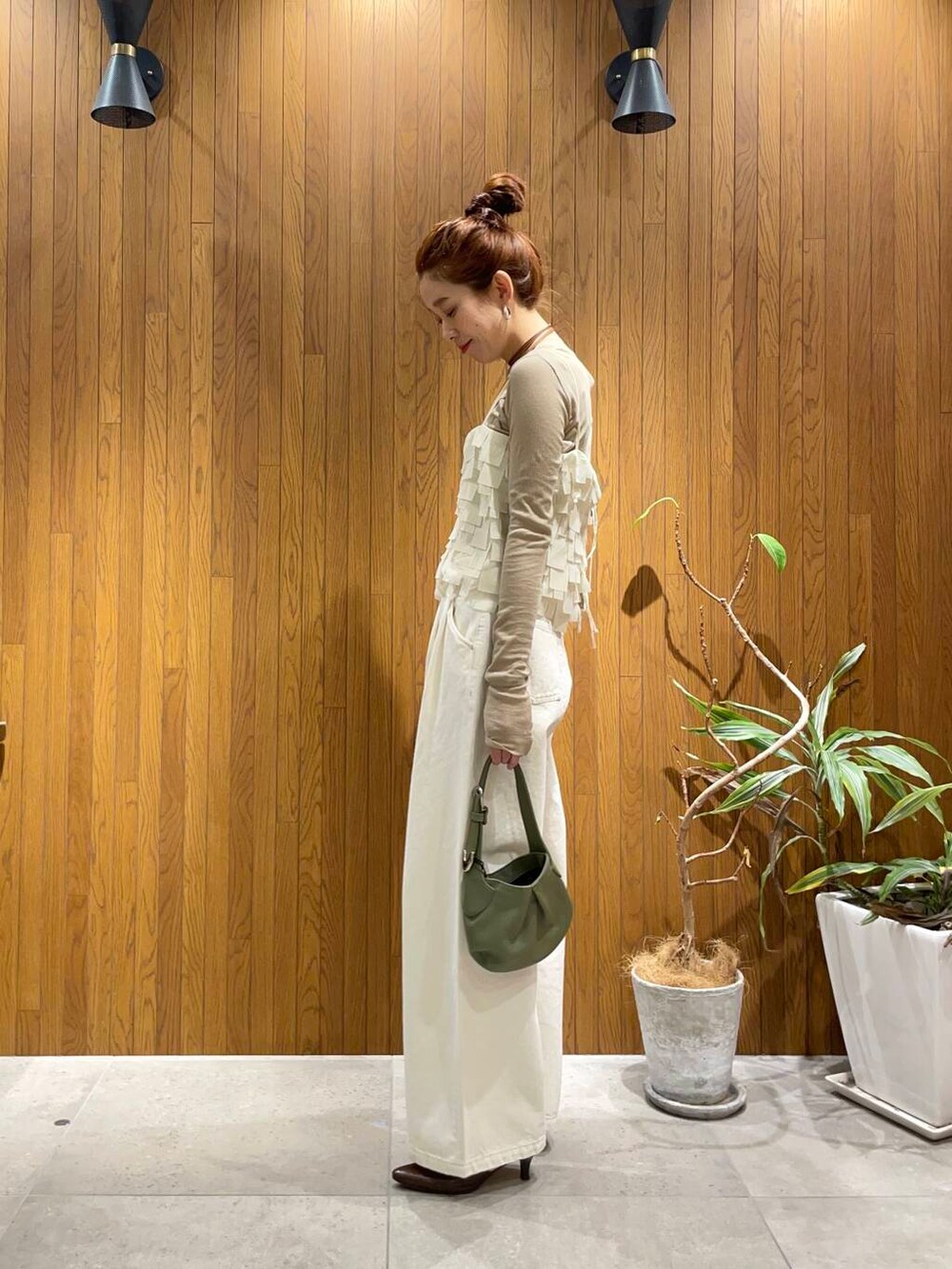 ホワイト系のデニムパンツ、ベージュ系のTシャツ/カットソー、グリーン系のハンドバッグを着用したレディースの冬コーディネートの2枚目の写真