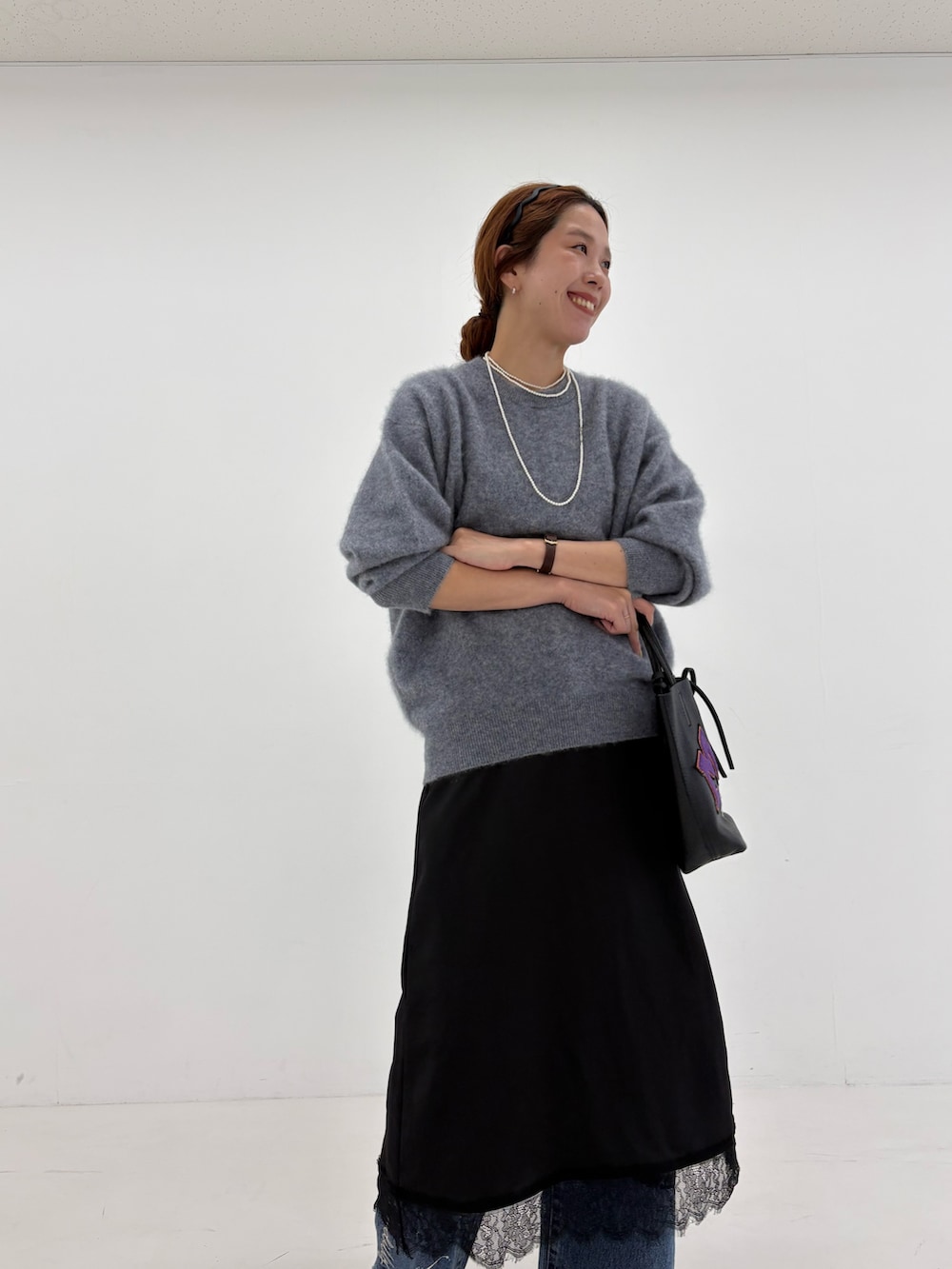 グレー系のニット/セーター、ブラック系のワンピース、ブルー系のデニムパンツを着用したレディースの秋コーディネートの8枚目の写真