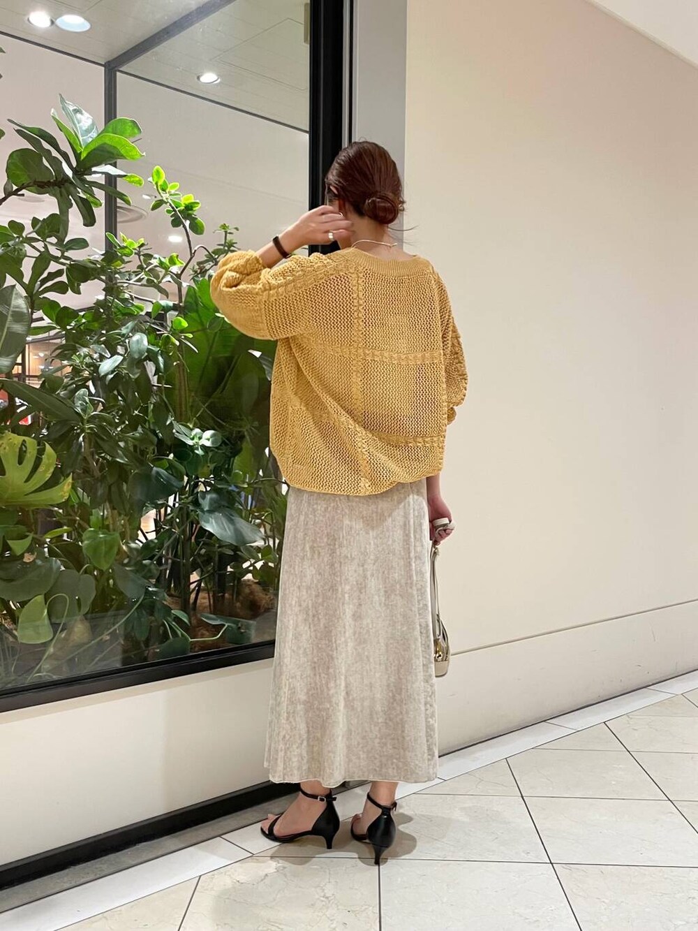 ホワイト系のショルダーバッグ、ベージュ系のスカート、イエロー系のニット/セーターを着用したレディースの冬コーディネートの4枚目の写真