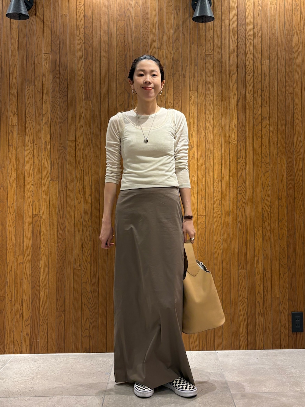 グレー系のスカート、ホワイト系のTシャツ/カットソー、ベージュ系のハンドバッグを着用したレディースの春コーディネートの7枚目の写真
