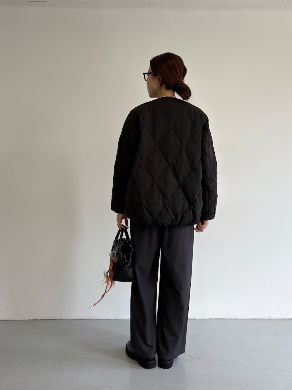 ブラック系のダウンジャケット/コート、グレー系のその他パンツ、ブラック系のローファーを着用したレディースの冬コーディネートの6枚目の写真