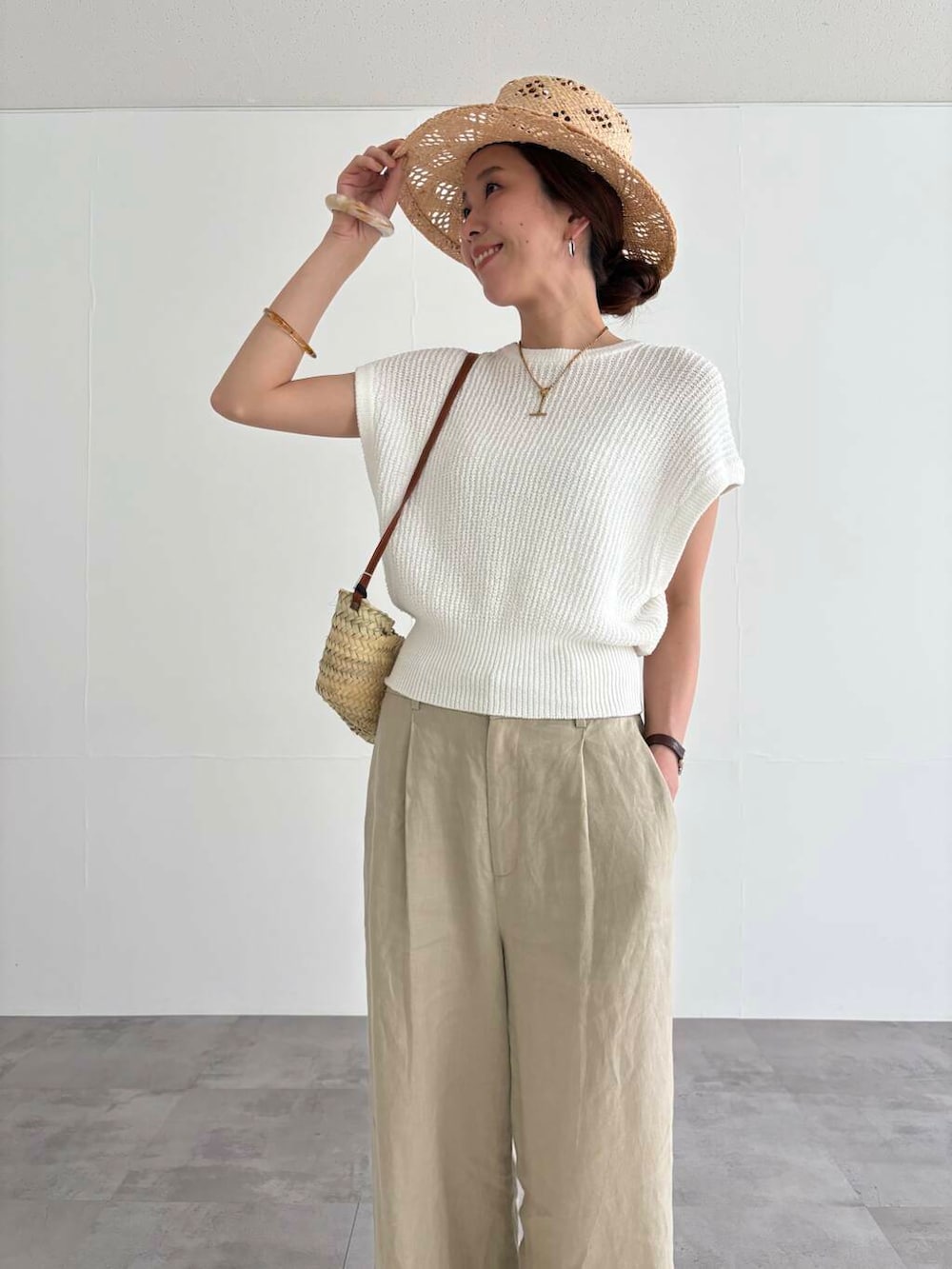 ベージュ系のその他パンツ、ホワイト系のベスト、ブラック系のサンダルを着用したレディースの夏コーディネートの5枚目の写真