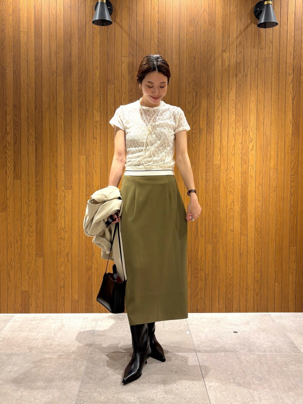 グリーン系のスカート、ブラック系のブーツ、ホワイト系のその他アウターを着用したレディースの秋コーディネートの6枚目の写真