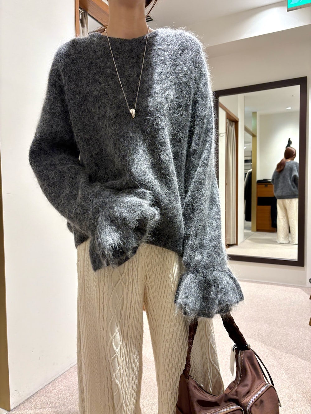 レッド系のショルダーバッグ、グレー系のニット/セーターを着用したレディースの冬コーディネートの5枚目の写真