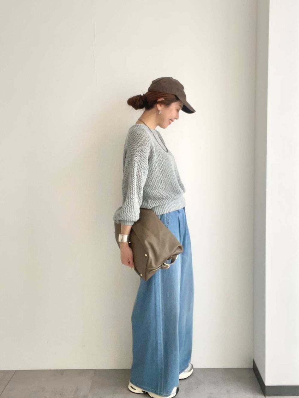 ベージュ系のボストンバッグ、グレー系のニット/セーター、ホワイト系のスニーカーを着用したレディースの春コーディネートの3枚目の写真