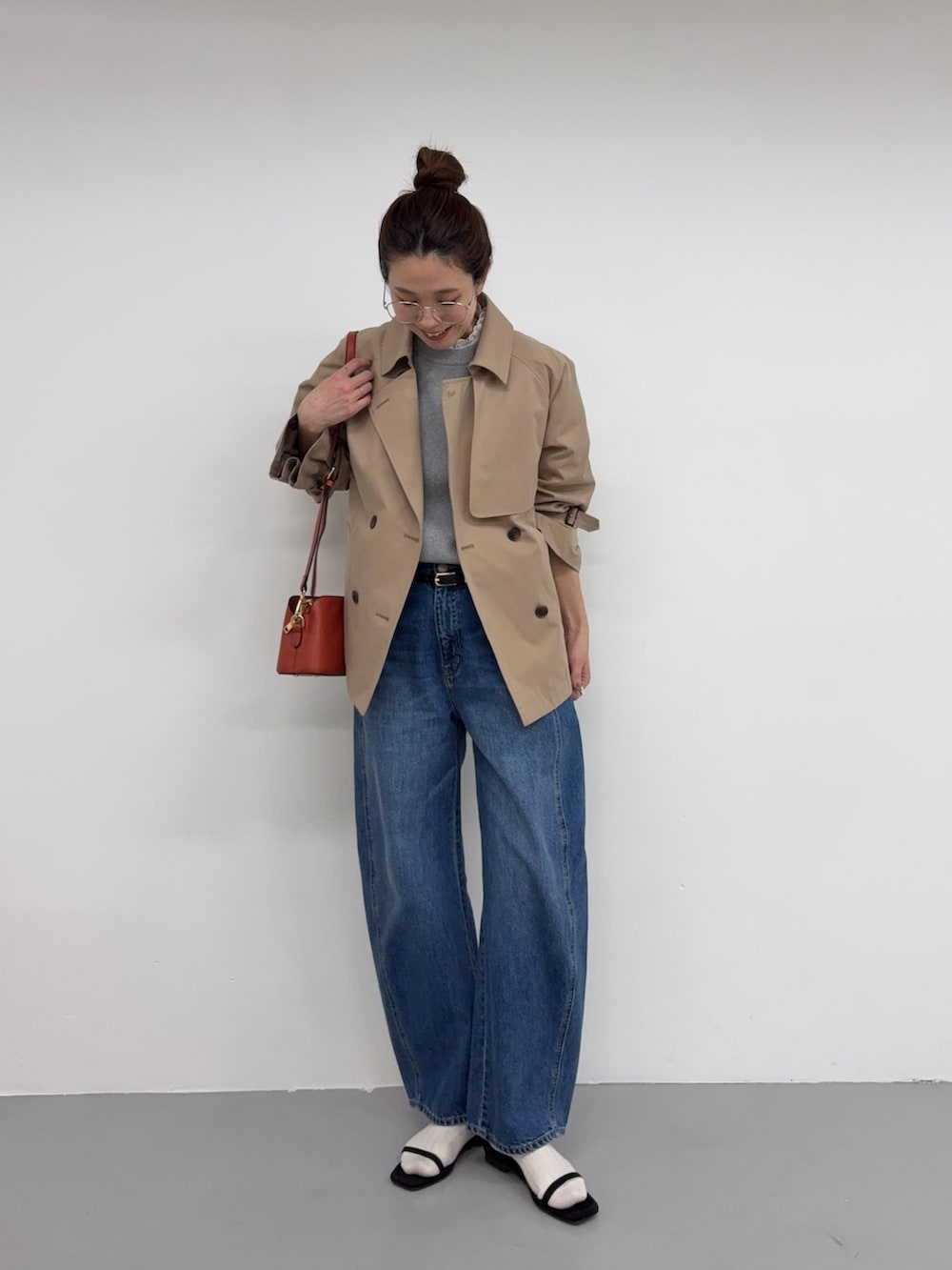 ベージュ系のトレンチコート、ブルー系のデニムパンツ、オレンジ系のショルダーバッグを着用したレディースの冬コーディネートの4枚目の写真