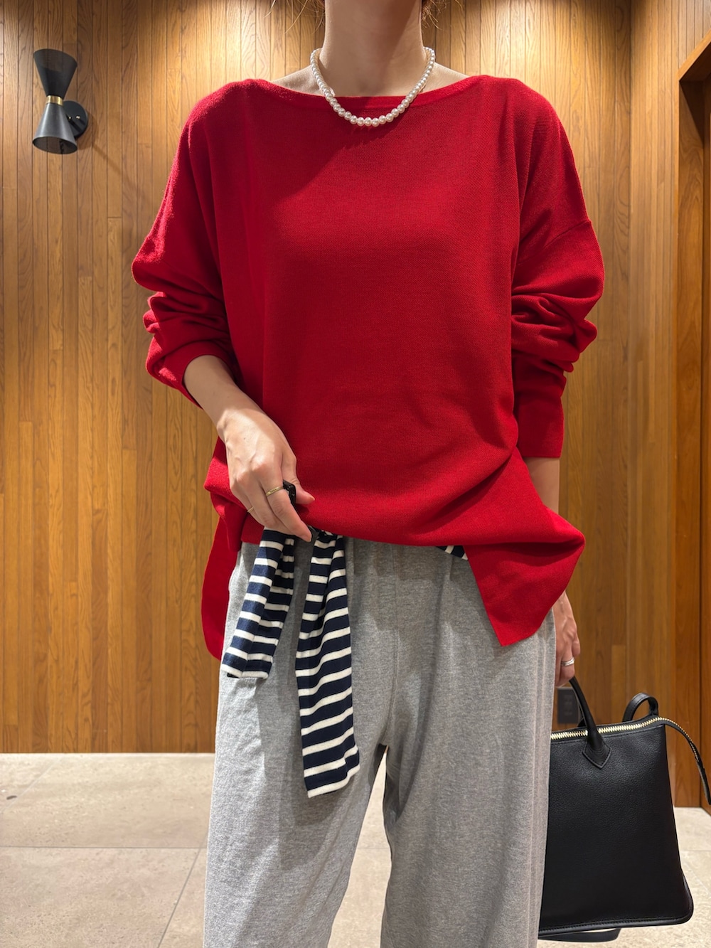 レッド系のニット/セーター、ブルー系のTシャツ/カットソー、グレー系のその他パンツを着用したレディースの秋コーディネートの6枚目の写真