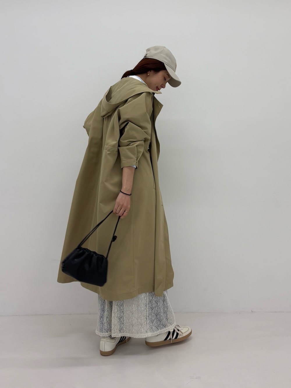 ホワイト系のスカート、ベージュ系のトレンチコート、ホワイト系のスニーカーを着用したレディースの春コーディネートの4枚目の写真