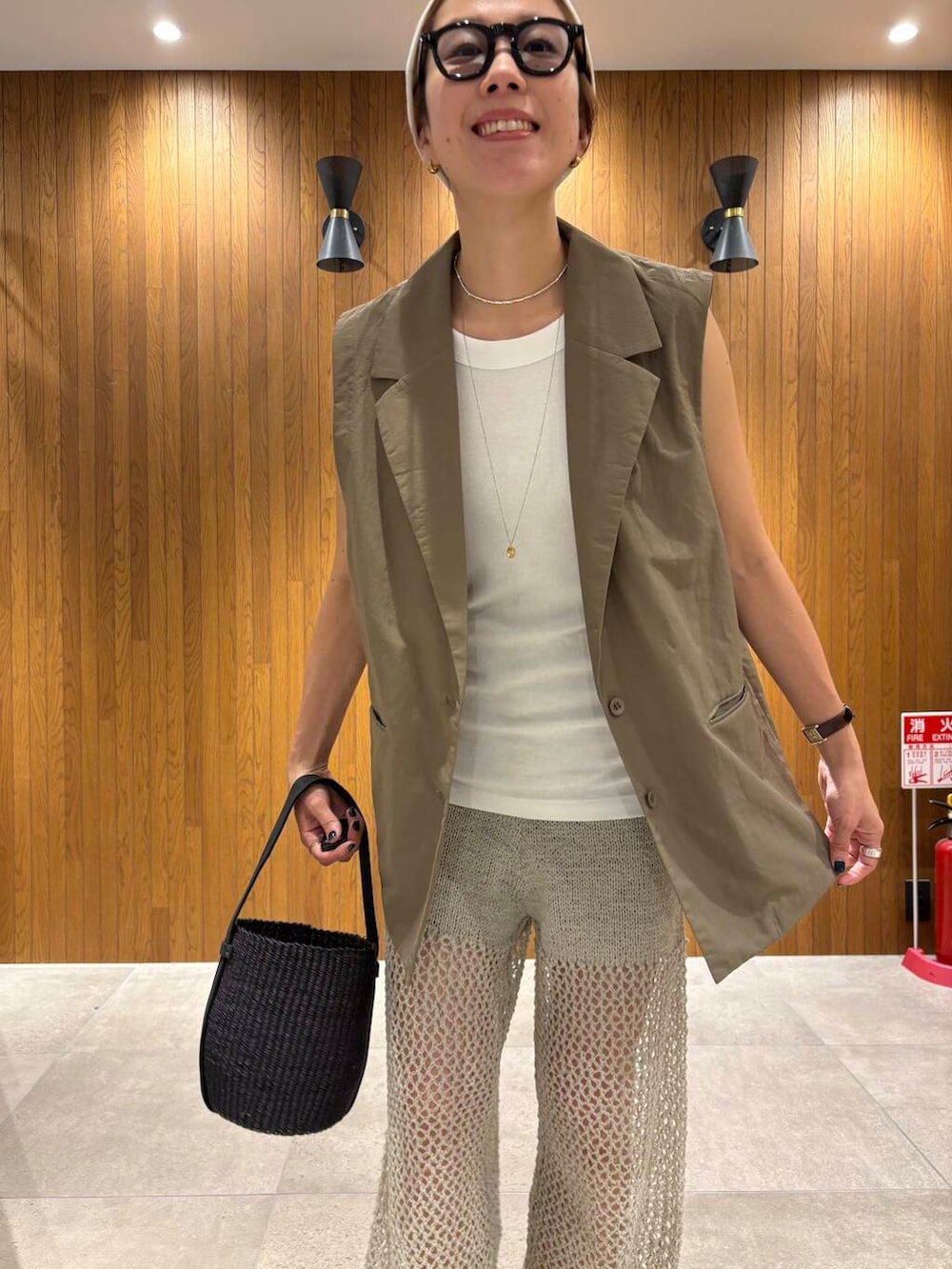 ブラック系のかごバッグ、ゴールド系のサンダル、グレー系のその他パンツを着用したレディースの夏コーディネートの7枚目の写真