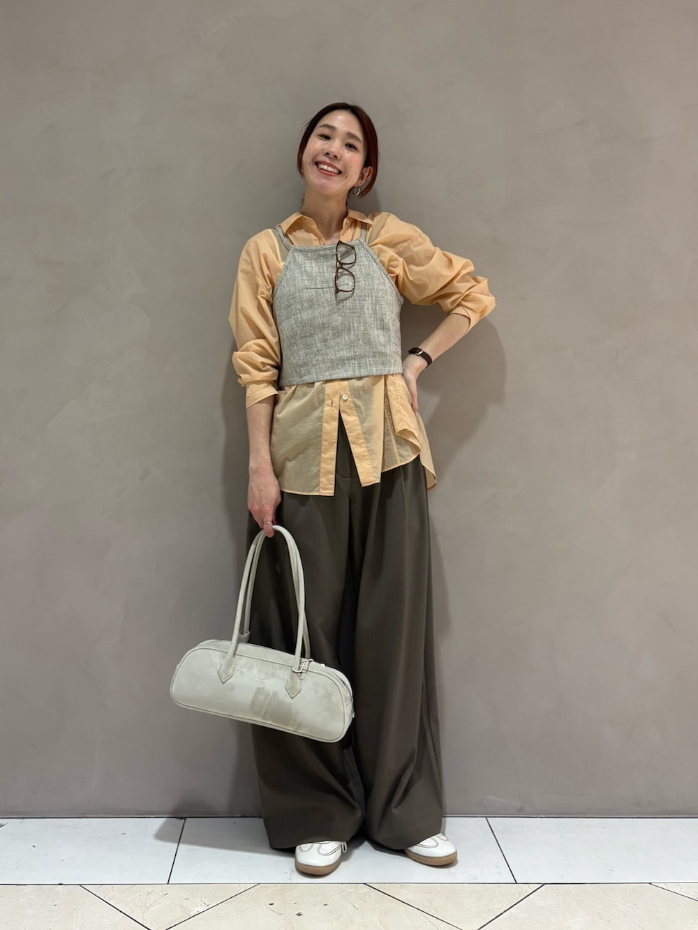 オレンジ系のシャツ/ブラウス、ベージュ系のその他トップス、ホワイト系のスニーカーを着用したレディースの春コーディネートの4枚目の写真