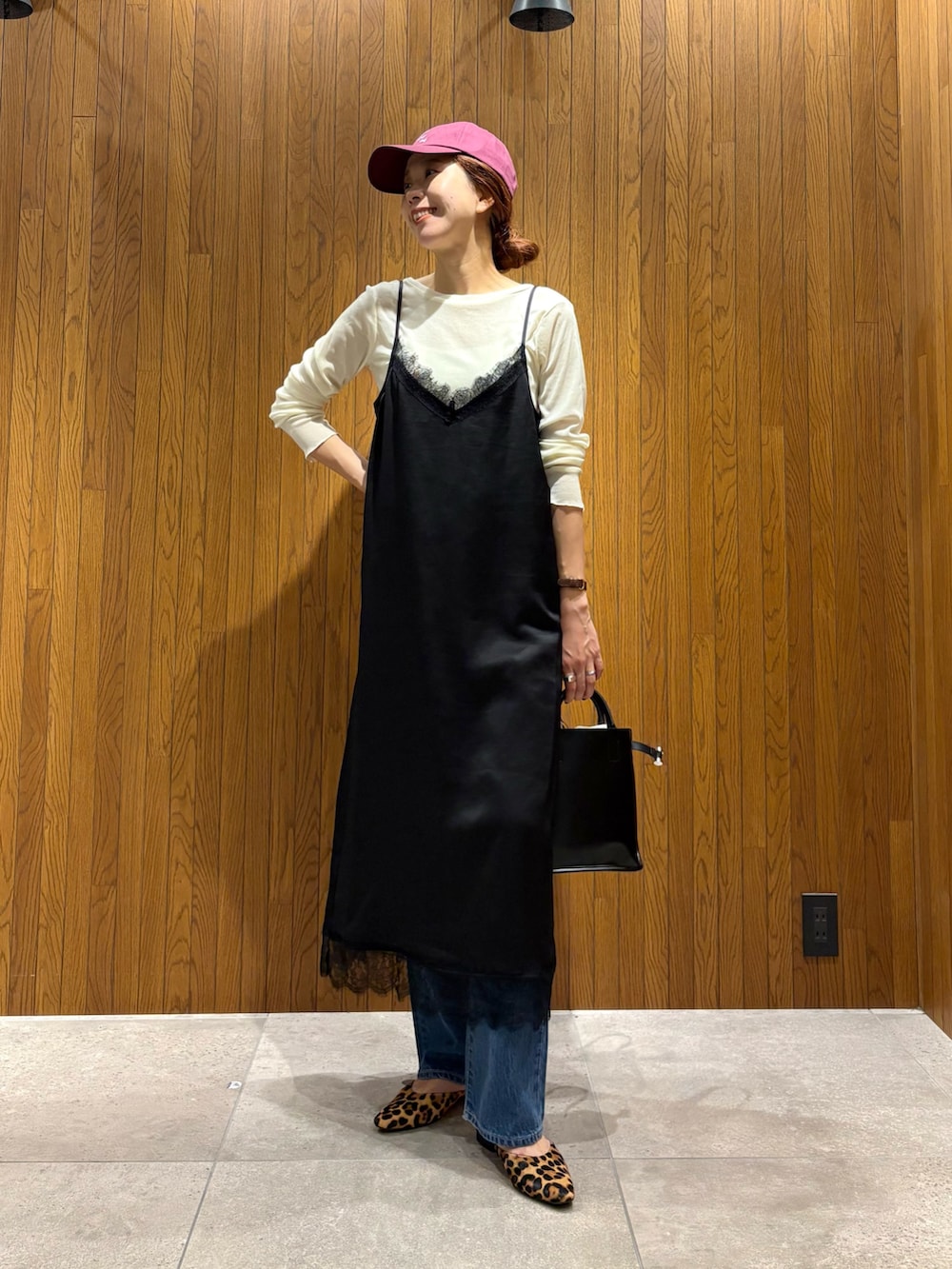 ブラック系のワンピース、ブルー系のデニムパンツ、ブラック系のショルダーバッグを着用したレディースの秋コーディネートの5枚目の写真