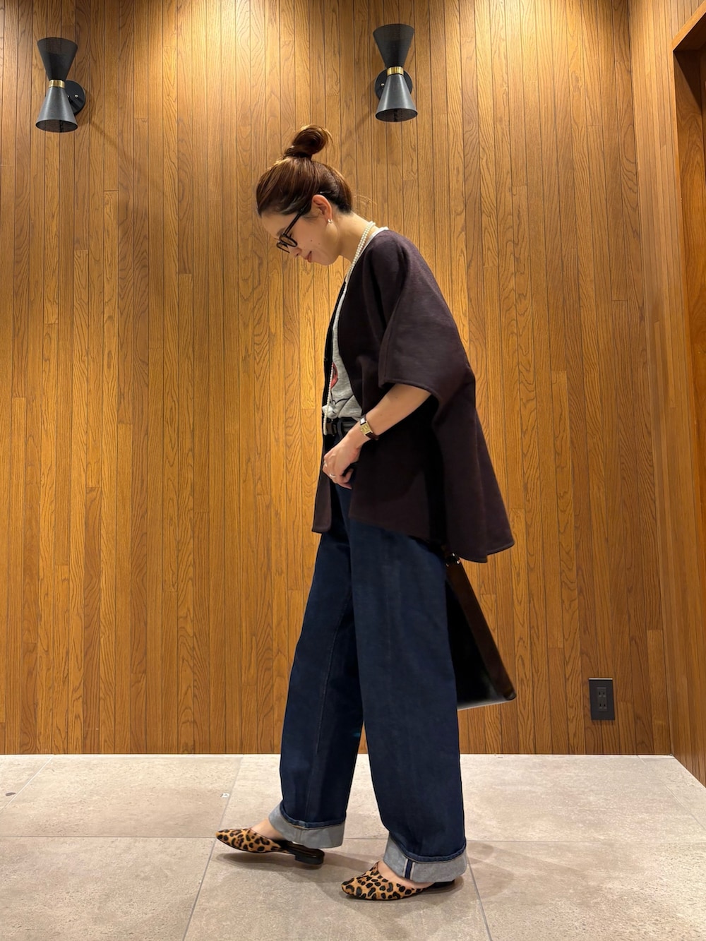 レッド系のポンチョ、ブルー系のデニムパンツ、ブラック系のトートバッグを着用したレディースの秋コーディネートの2枚目の写真