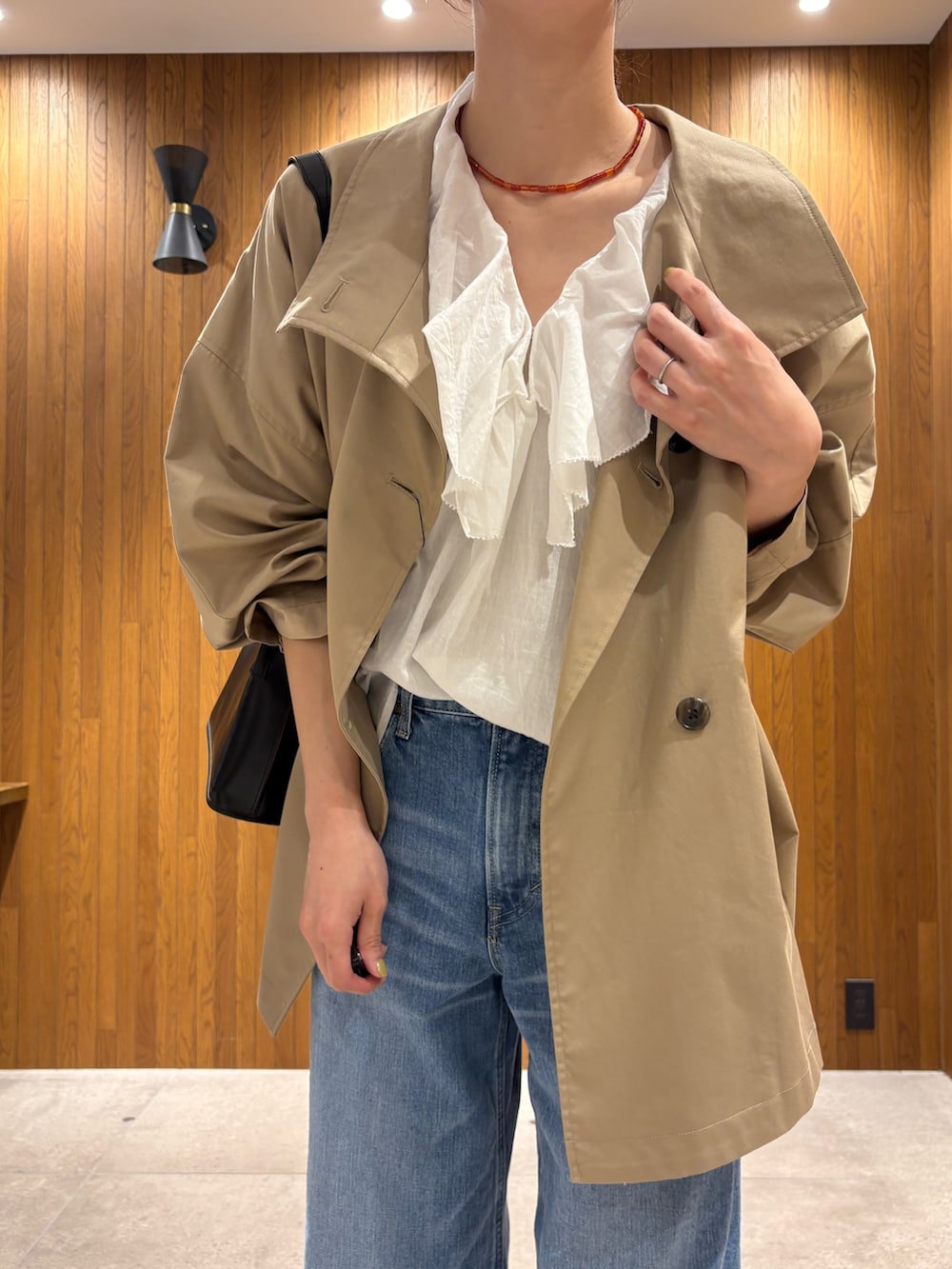 ベージュ系のトレンチコート、ホワイト系のシャツ/ブラウス、ブルー系のデニムパンツを着用したレディースの春コーディネートの6枚目の写真